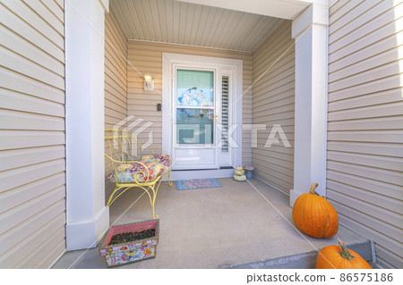 House exterior with beige vinyl lap siding and glass storm door over the wreath on the front door 86575186