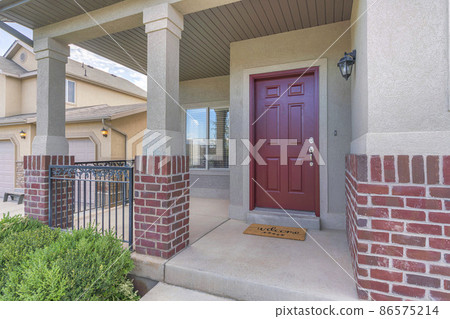 Red front door of a house with red bricks siding and railings at the porch Red front door of a house with red bricks siding and railings at the porch 86575214
