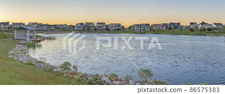 Oquirrh Lake with covered dock and surrounded by grass at Daybreak, Utah 86575383