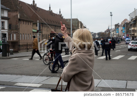 Strasbourg - France - 22 January 2022 - Portrait on back view of old woman making a bad gesture in the street against the covid-19 protesters 86575678