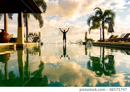A man standing at the edge of infinity pool A man standing at the edge of infinity pool 86575747