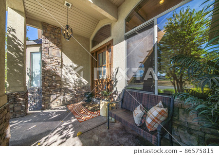 Rustic front entrance of a house with stone veneer siding and reflective arched glass window 86575815