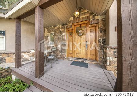 Porch of a house with outdoor chandelier and wooden column posts 86575818