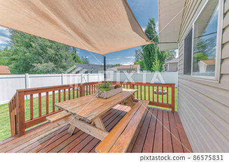 Outdoor patio with sunshade and wooden table with seats 86575831