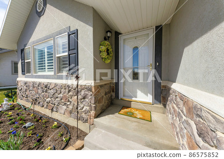 Entrance of a house with wreath beside the glass storm door over the white door with ornate glass Entrance of a house with wreath beside the glass storm door over the white door with ornate glass 86575852
