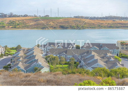 View of a subdivision houses from the top against the river and grassy land at the back 86575887