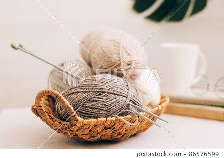 Natural wool in balls of various pastel colors in a wicker basket. Knitting threads close-up on a light background. Natural wool in balls of various pastel colors in a wicker basket. Knitting threads close-up on a light background. 86576599