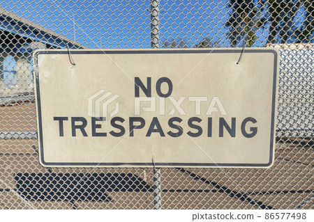 No trespassing sign on a mesh wire fence at Coronado, San Diego, California 86577498