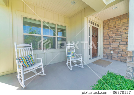 Front exterior of a house with wood beige siding and wooden front door with glass panes 86578137