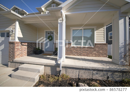 Porch of a house near the garage with vinyl wood and bricks siding 86578277
