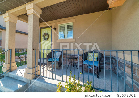 Exterior of a porch of a house with woven lounge seats and metal railings Exterior of a porch of a house with woven lounge seats and metal railings 86578301