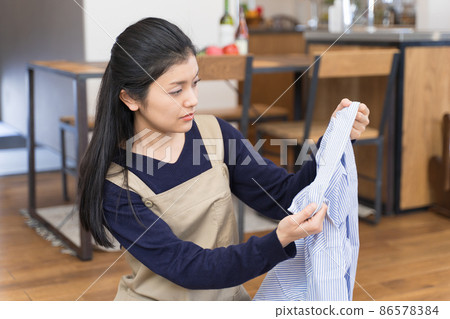 Young woman looking at shirt collar stains 86578384