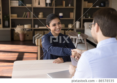 Smiling young Indian woman shaking hands with hr manager. Smiling young Indian woman shaking hands with hr manager. 86578535