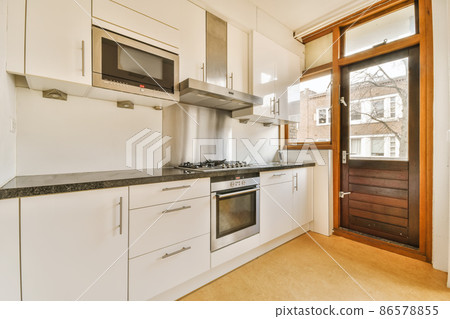 Interior of a stylish modern kitchen room with the wooden brown door Interior of a stylish modern kitchen room with the wooden brown door 86578855