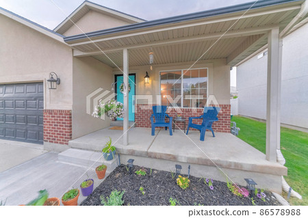 Colorful facade of a house with front yard garden and garage with sectional gray door Colorful facade of a house with front yard garden and garage with sectional gray door 86578988