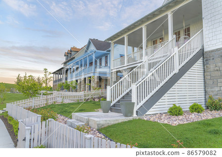 Three large houses with white picket fence and verandas at the entrance in Daybreak, Utah 86579082