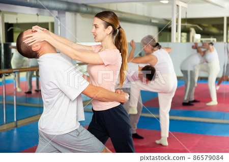 Girl using painful technique for eyes to opponent in self-defense training 86579084