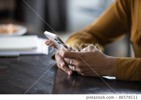 Hands of young dark skinned woman using app on phone 86579111