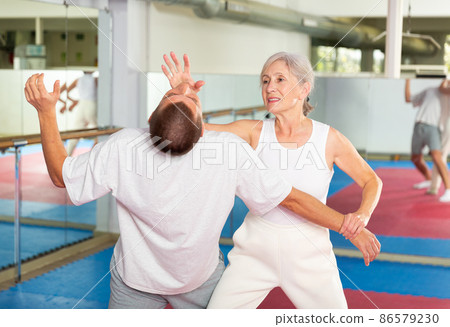 Senior woman performing chin strike during self-defence training 86579230