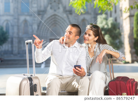 Couple of travelers resting on bench, looking at sights 86579247