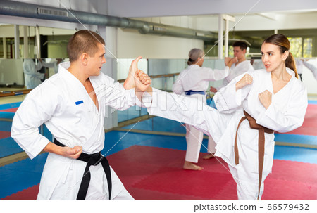 Man and woman in kimono sparring during group karate training 86579432