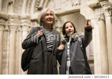 Preteen girl visiting museum of ancient sculpture her grandmother Preteen girl visiting museum of ancient sculpture her grandmother 86580013