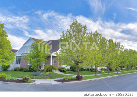 Corner house with bricks siding, flowers and trees on the lawn at Daybreak, Utah Corner house with bricks siding, flowers and trees on the lawn at Daybreak, Utah 86580155