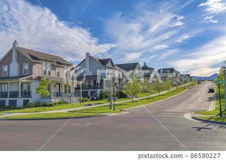 Row of large two-storey houses near the paved uphill road at Daybreak, Utah 86580227
