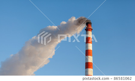 White thick smoke from the boiler room chimney. Smoke against the blue sky. Air pollution. Heating of the city. Industrial zone. 86581062