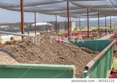 Garden soil with rake on top in a green metal tray 86581218