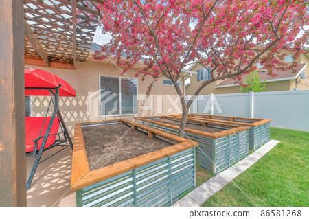 Growbeds at the backyard of a house with corrugated steel walls and wooden edge 86581268