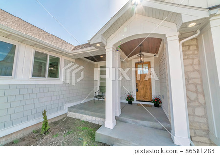 Front exterior of a house with wooden door and potted flowers at the doorstep Front exterior of a house with wooden door and potted flowers at the doorstep 86581283