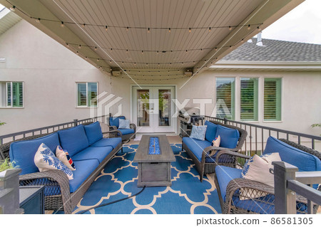 Outdoor deck with string lights, barbecue griller and fire pit table with blue fire glass Outdoor deck with string lights, barbecue griller and fire pit table with blue fire glass 86581305