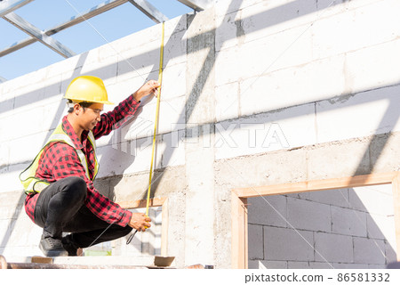 Construction worker or contractor man using measuring tape checking from steel roof frame to the door Construction worker or contractor man using measuring tape checking from steel roof frame to the door 86581332