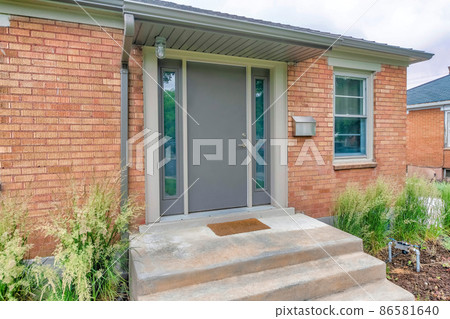 Side view of an entrance of a house with bricks and tall grasses at the front Side view of an entrance of a house with bricks and tall grasses at the front 86581640