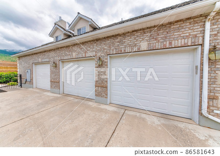Three car garage doors exterior with bricks and lamps 86581643