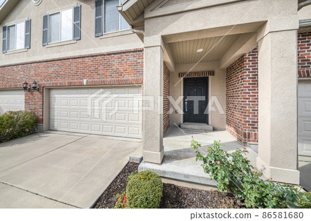 Black front door of a townhouse in the middle of garaga doors 86581680