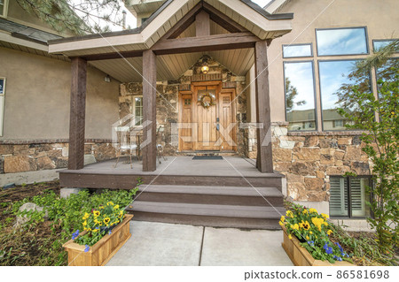 Entrance of a house with flowers on the wooden boxes at the front of the porch Entrance of a house with flowers on the wooden boxes at the front of the porch 86581698