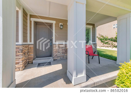 Porch of a house with white column posts and red arm chair Porch of a house with white column posts and red arm chair 86582016