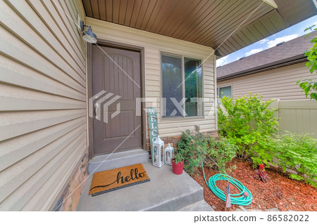 Facade of house with beige vinyl lap siding and gray front door near the window 86582022