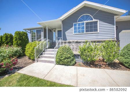 Facade of a house with shrubs, trees and lawn at the front Facade of a house with shrubs, trees and lawn at the front 86582092