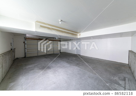 Garage interior with automatic sectional door and white fire door Garage interior with automatic sectional door and white fire door 86582118