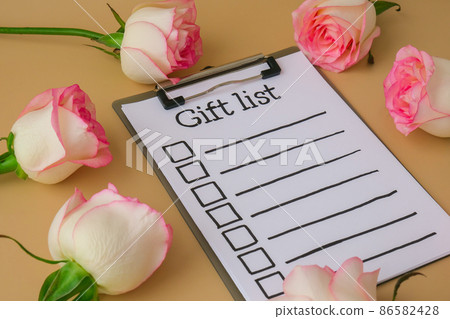 GIFT LIST on paper note. Delicate pink roses on beige background. Minimal trendy composition. Romantic pastel pink rose flowers. Neutral earth tones. Preparation for Valentines day 86582428