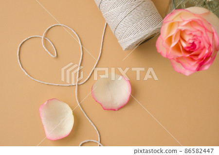 Tender pink roses with spool of white cotton rope in heart shape on beige background. Minimal trendy composition. Neutral earth tones. Greeting card for Valentines Mothers Womens day Tender pink roses with spool of white cotton rope in heart shape on beige background. Minimal trendy composition. Neutral earth tones. Greeting card for Valentines Mothers Womens day 86582447