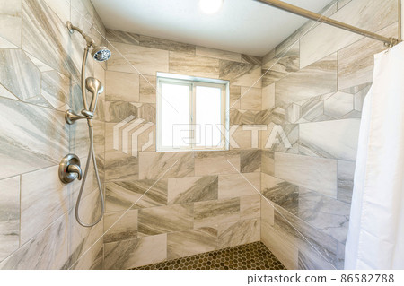 Shower stall interior with marble tile surround and small hexagon pattern tile flooring Shower stall interior with marble tile surround and small hexagon pattern tile flooring 86582788
