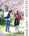 A girl turning around on the cherry blossom road and a boy in the back 86583130