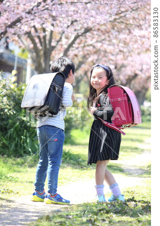 A girl turning around on the cherry blossom road and a boy in the back 86583130