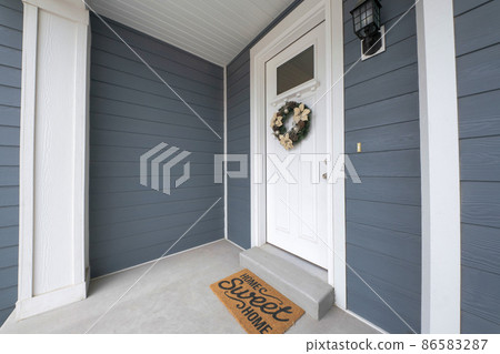 White front door of a house with wreath below the window panel 86583287