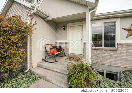 Exterior of an entrance of a house with white front door and rocking bench with pillows 86583621