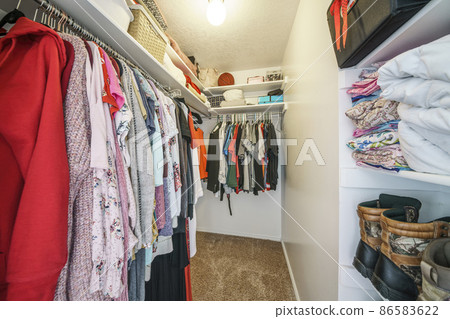 Narrow walk-in closet interior with clothes, shoes and bags 86583622